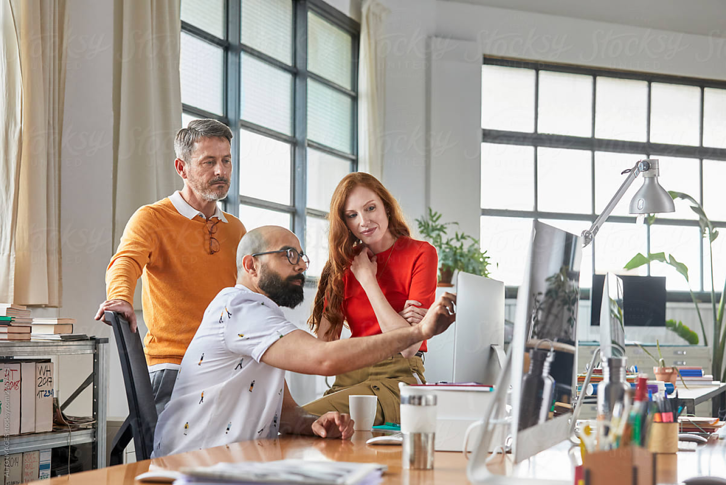 Three people around a desktop collaborating and demonstrating on screen