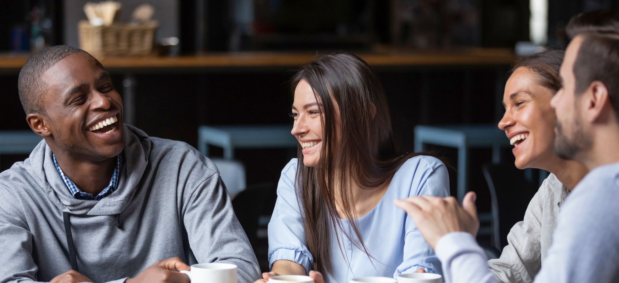 Four smiling people conversing over coffee