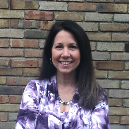 Lori smiling in front of a brick wall