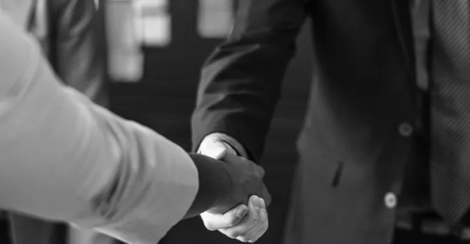 Two person shaking hands in grayscale photo