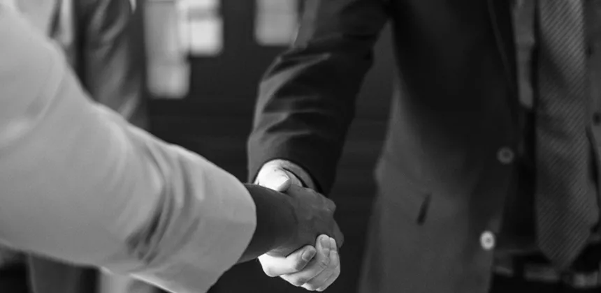 Two person shaking hands in grayscale photo